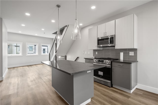 kitchen with a center island, stainless steel appliances, pendant lighting, light hardwood / wood-style floors, and gray cabinets