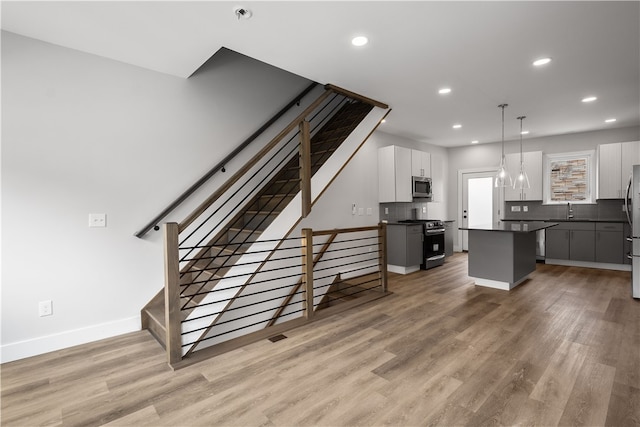 kitchen featuring appliances with stainless steel finishes, a center island, decorative light fixtures, and white cabinetry