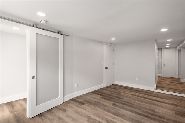 basement featuring a barn door and hardwood / wood-style flooring