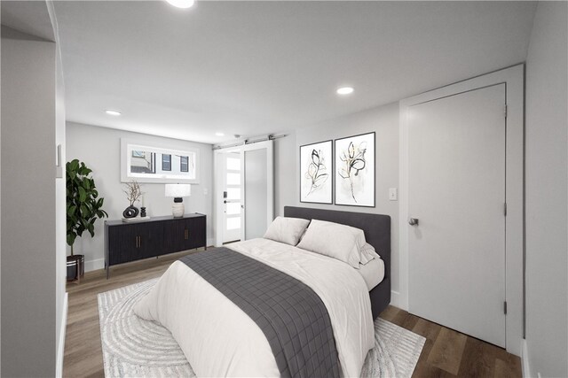 bedroom with a barn door and wood-type flooring