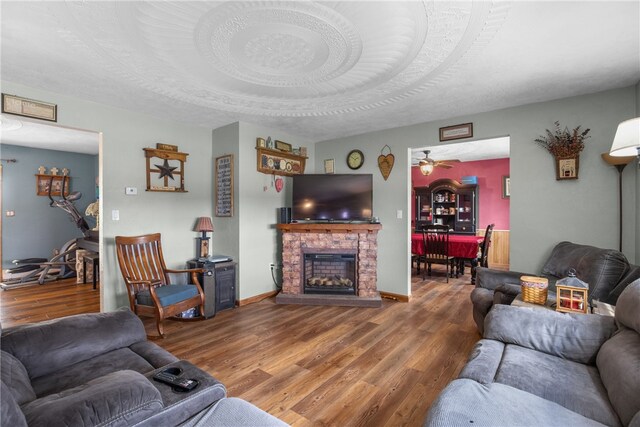 living room featuring ceiling fan, hardwood / wood-style flooring, a brick fireplace, and a textured ceiling