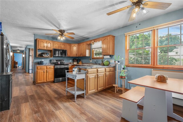 kitchen with a textured ceiling, dark wood-type flooring, sink, stainless steel appliances, and ceiling fan