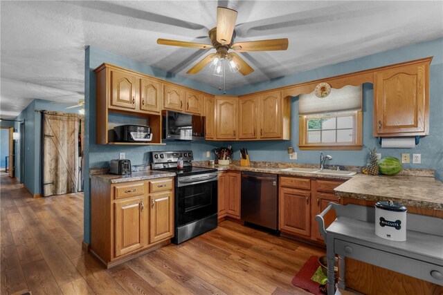 kitchen with ceiling fan, hardwood / wood-style flooring, appliances with stainless steel finishes, and sink