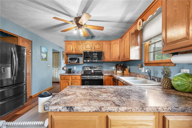 kitchen featuring kitchen peninsula, stainless steel appliances, ceiling fan, hardwood / wood-style flooring, and sink