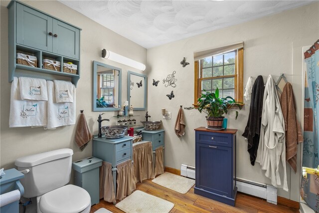 bathroom featuring a baseboard radiator, wood-type flooring, sink, and toilet