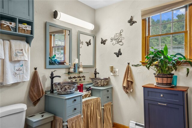 bathroom with toilet, a baseboard heating unit, and sink