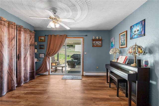 miscellaneous room with a baseboard radiator, ceiling fan, hardwood / wood-style floors, and a textured ceiling