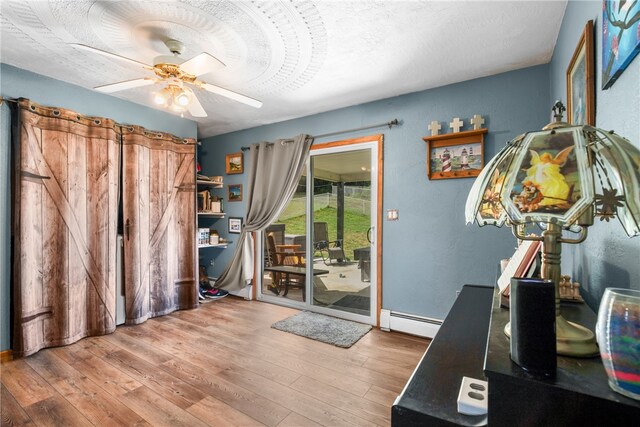 interior space with a baseboard radiator, ceiling fan, hardwood / wood-style flooring, and a textured ceiling