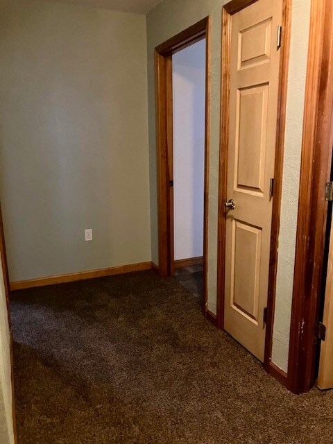 hallway featuring dark colored carpet