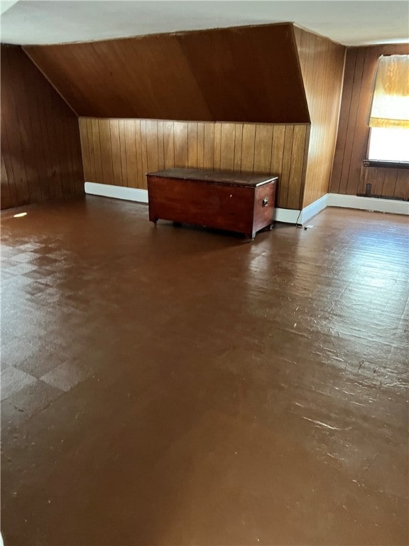 bonus room featuring wooden walls, vaulted ceiling, and concrete flooring