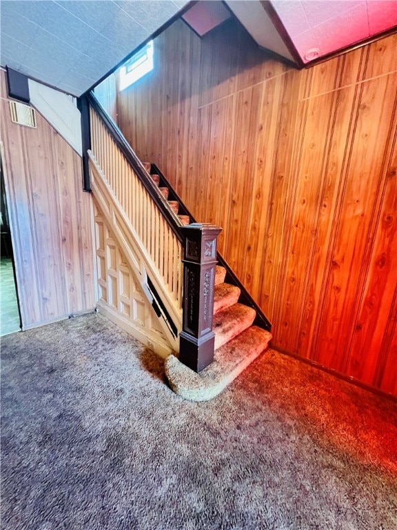 staircase featuring carpet and wood walls