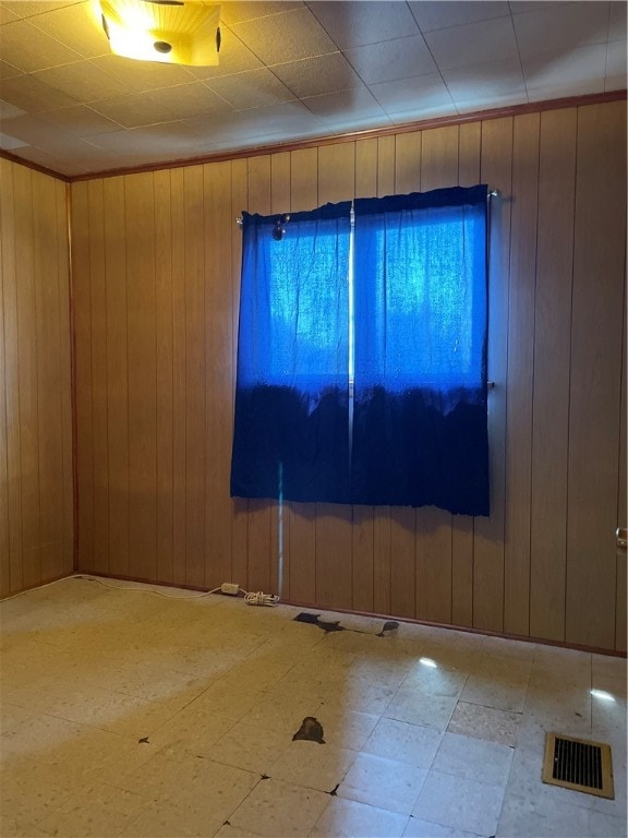 tiled spare room featuring wood walls