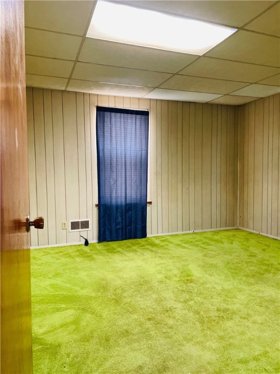 spare room featuring carpet floors, a drop ceiling, and wood walls