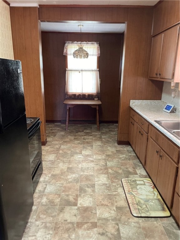 kitchen with light tile patterned floors, hanging light fixtures, stove, and black fridge