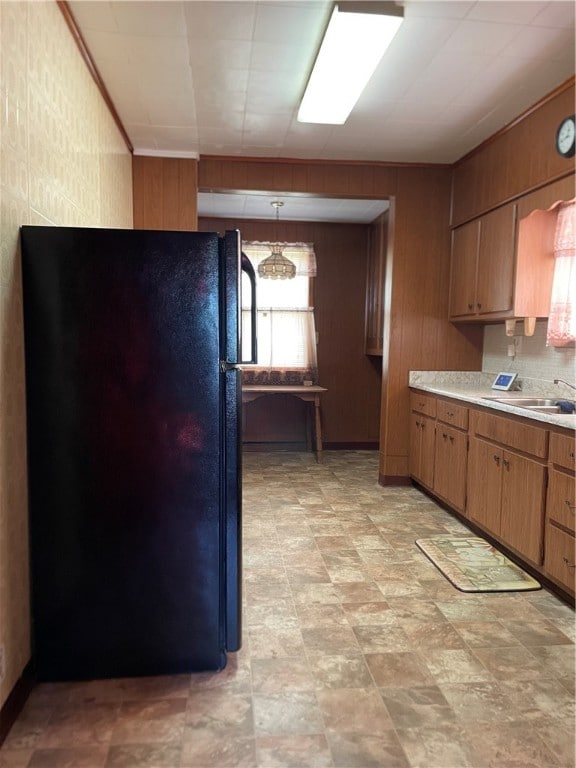 kitchen featuring black fridge, hanging light fixtures, sink, and light tile patterned floors