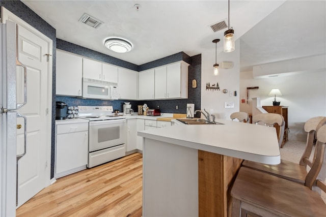 kitchen with decorative light fixtures, kitchen peninsula, sink, white appliances, and white cabinetry