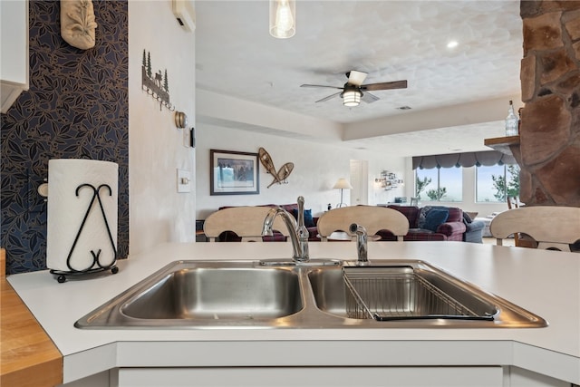 kitchen featuring ceiling fan, sink, and white cabinetry