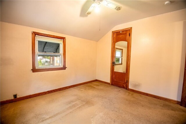 spare room with lofted ceiling, light colored carpet, a wealth of natural light, and ceiling fan