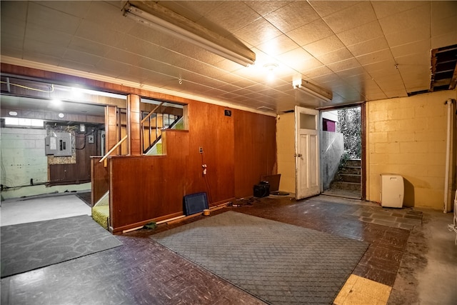 basement featuring wood walls and electric panel