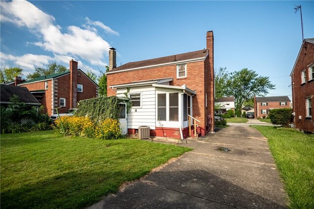 rear view of property with a yard and central air condition unit