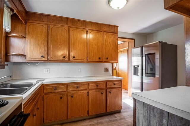 kitchen with stainless steel fridge, stove, light wood-type flooring, and sink