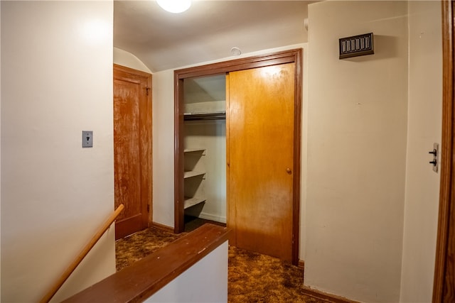 hall featuring dark colored carpet