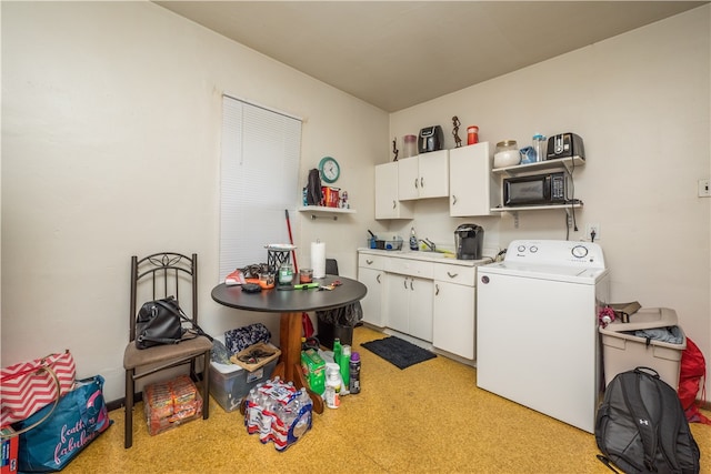 interior space featuring washer / dryer, sink, and white cabinetry