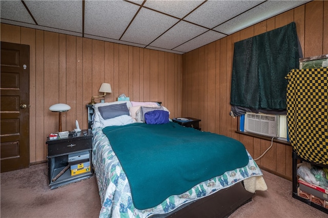 carpeted bedroom with a drop ceiling, wooden walls, and cooling unit