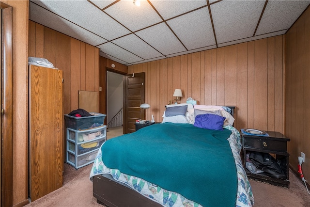 bedroom featuring a drop ceiling, carpet floors, and wooden walls