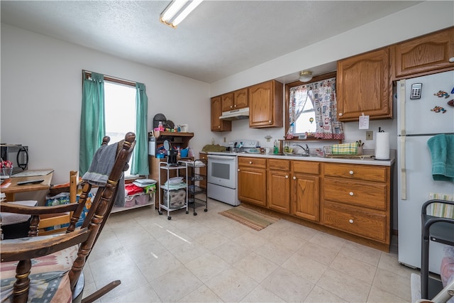 kitchen featuring light tile patterned floors, white appliances, and sink