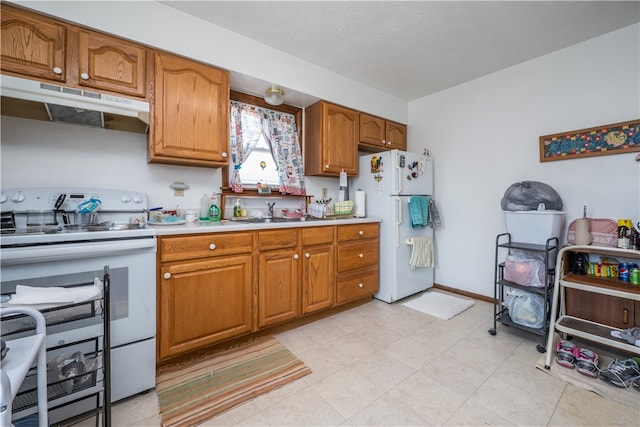 kitchen with white appliances, sink, light tile patterned flooring, and a textured ceiling