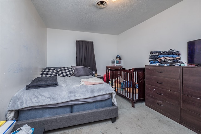 bedroom featuring a textured ceiling and light carpet