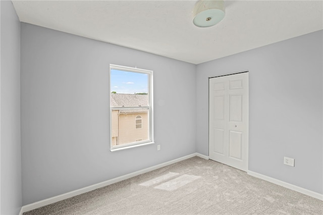 spare room with light carpet and baseboards