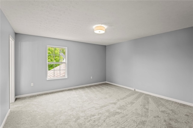 unfurnished room featuring light carpet, a textured ceiling, and baseboards