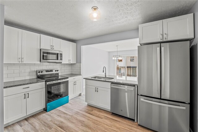 kitchen featuring light hardwood / wood-style flooring, appliances with stainless steel finishes, sink, and white cabinetry