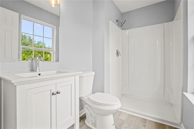 full bathroom with toilet, a shower, wood finished floors, and vanity