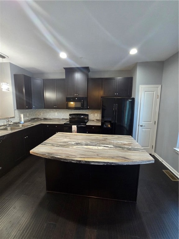 kitchen featuring dark wood-type flooring, black appliances, a center island, tasteful backsplash, and sink