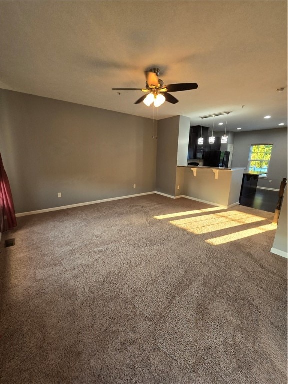 unfurnished living room featuring ceiling fan and carpet floors