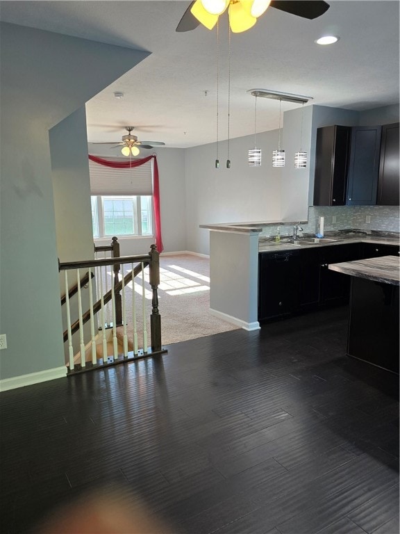 kitchen with decorative light fixtures, ceiling fan, backsplash, sink, and kitchen peninsula