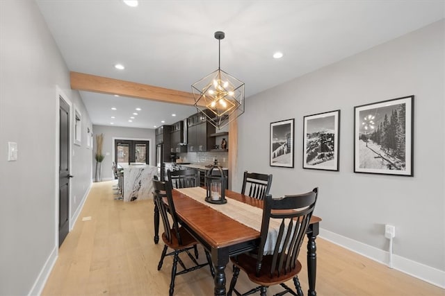 dining space with beamed ceiling, light hardwood / wood-style floors, and an inviting chandelier