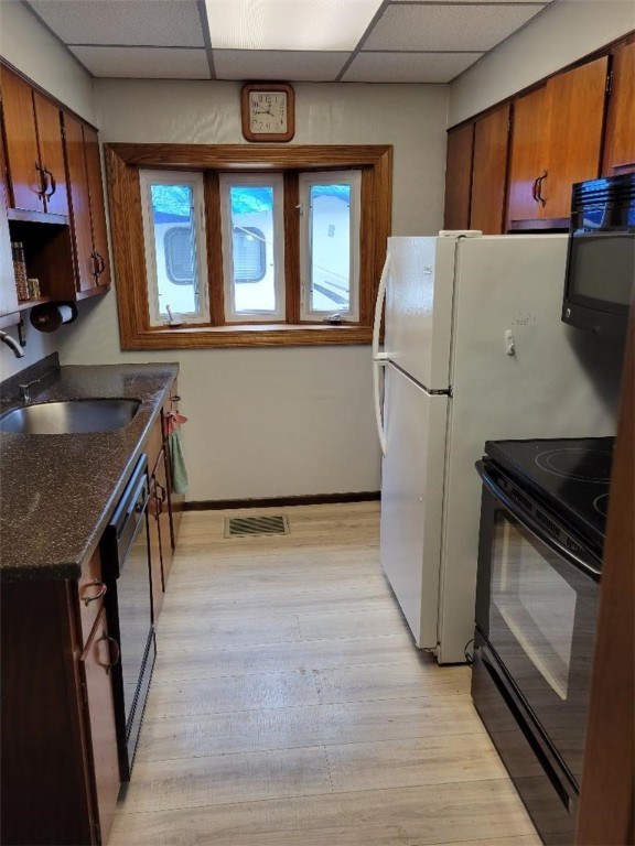 kitchen featuring a paneled ceiling, sink, light wood-type flooring, and black appliances