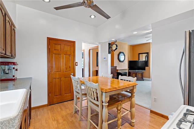 dining area featuring light wood-type flooring, sink, and ceiling fan