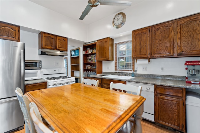 kitchen with white appliances, a breakfast bar, ceiling fan, sink, and light hardwood / wood-style flooring