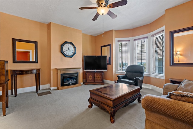 living room with ceiling fan, a textured ceiling, and carpet floors