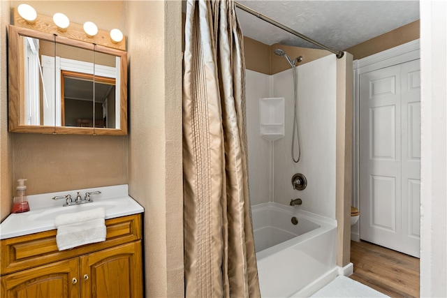 full bathroom featuring a textured ceiling, shower / bath combo with shower curtain, hardwood / wood-style flooring, toilet, and vanity