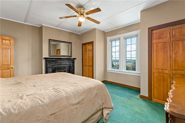 carpeted bedroom featuring ceiling fan and a stone fireplace