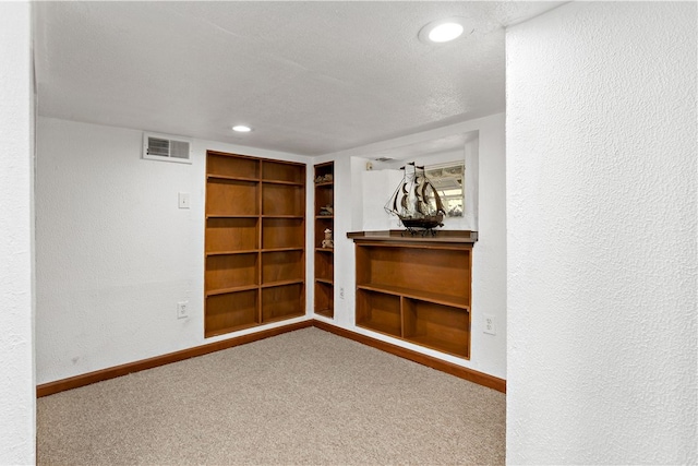 spare room featuring a textured ceiling, carpet, and built in features