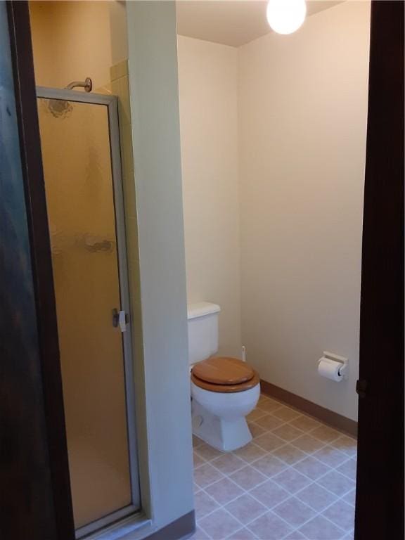 bathroom with baseboards, a shower stall, toilet, and tile patterned floors