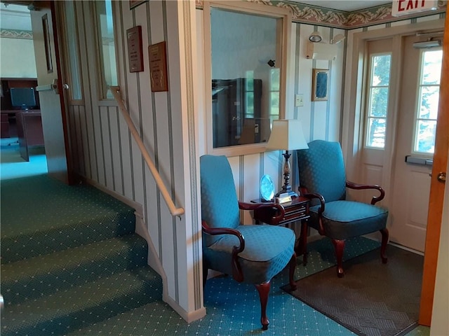 living area featuring wallpapered walls, stairs, and carpet flooring