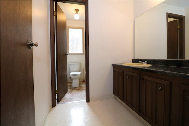 half bathroom with vanity, toilet, and baseboards